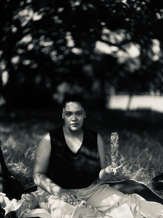 A woman seated on a picnic blanket, photographed in black and white.