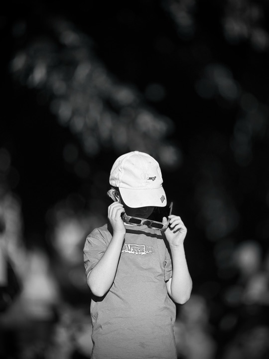 A child looking through a small camera, photographed in black and white.