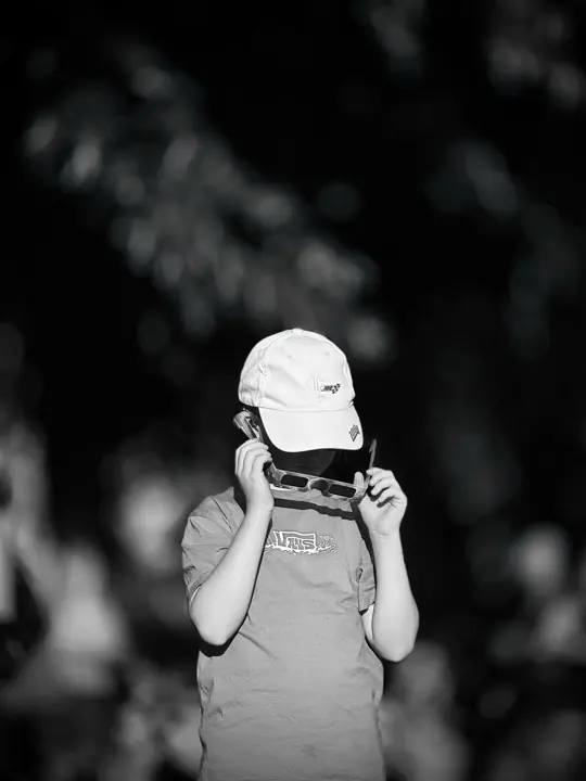 A child looking through a small camera, photographed in black and white.