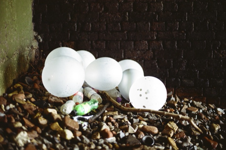 Discarded white globes resting beneath a brick wall.