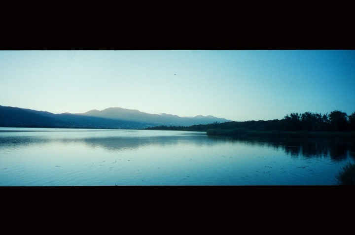 A still lake and mountain ridge at blue hour.
