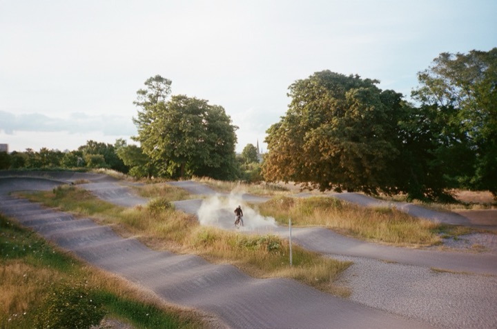 Two figures following a winding path through open grassland.