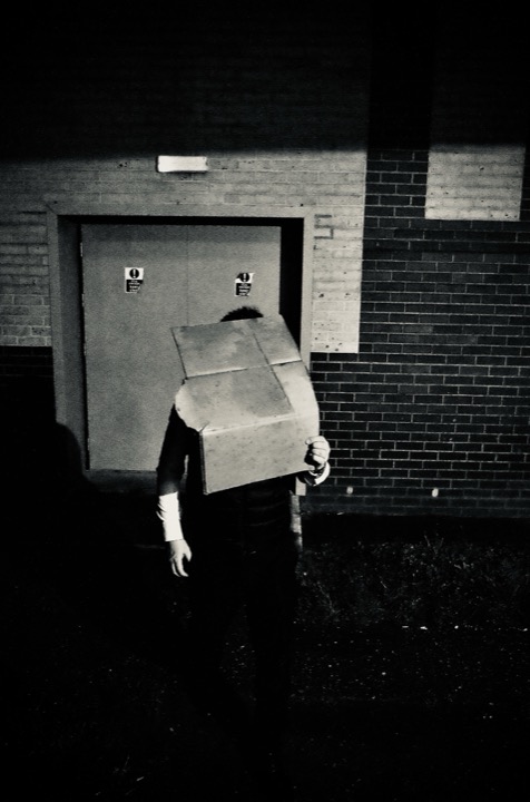 A person carrying a box toward a closed industrial door.