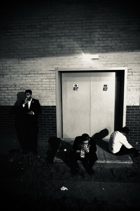 A small group gathered outside a closed doorway at night.
