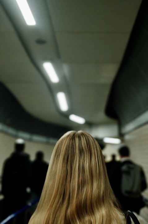 A commuter seen from behind beneath underground lights.